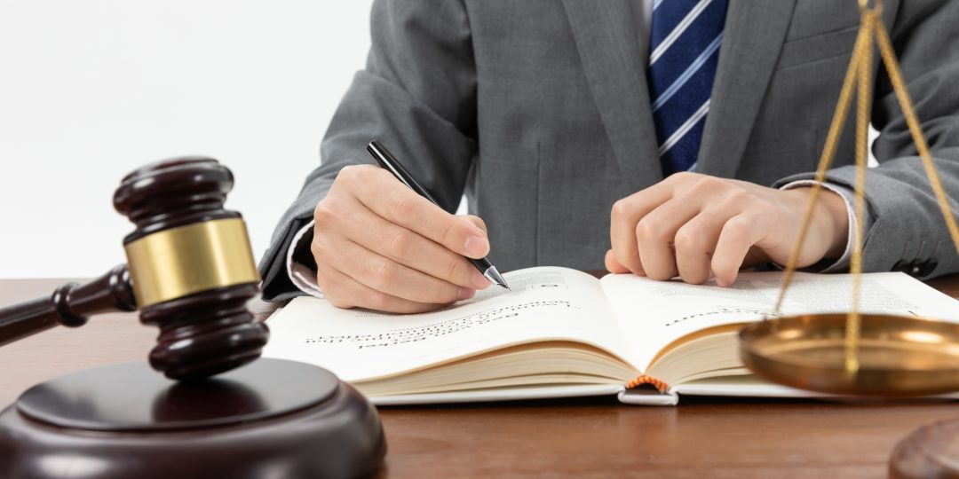 closeup-shot-person-writing-book-with-gavel-table-1080x540.jpg